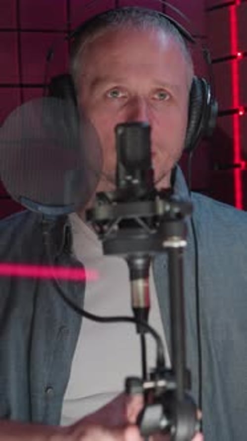 Man in Studio Adjusting Microphone with Assistance