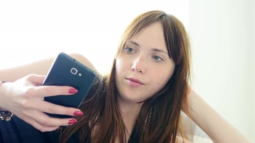 Woman Lying Down Using Smartphone Indoors