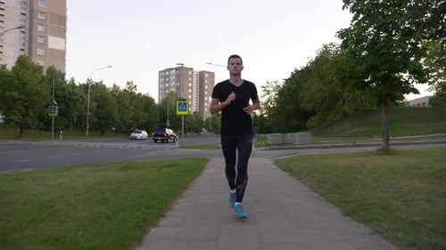 Man Running on Sidewalk in Urban Environment