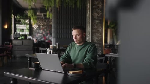 Homme caucasien adulte assis dans un café et travaillant avec un ordinateur portable Portrait d'un programmeur indépendant