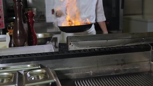 Chef Cooking Food with Flames in Restaurant Kitchen