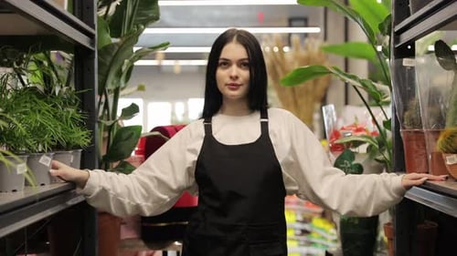 Young Female Florist Examining Plants in Garden Center