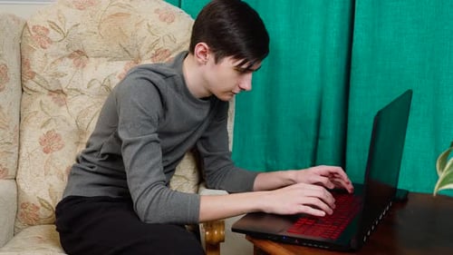Young Adult Works on Laptop at Home