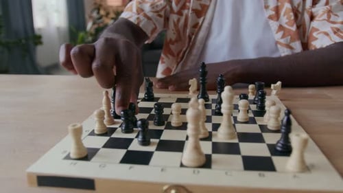 Hand Moves Black Chess Piece on Chessboard