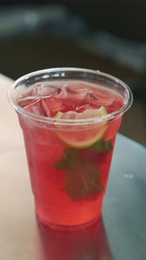 A Refreshing Berry Beverage with Lime and Mint Served in a Clear Cup for Enjoyment