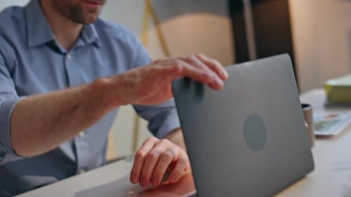 Tired Man Closing Laptop at Desk