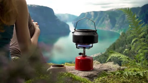 Woman Sits In Nature With Red Gas Stove