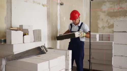Bricklayer Using Rubber Mallet Hammer to Tap and Level Concrete Blocks Wall Contractor Uses Precise