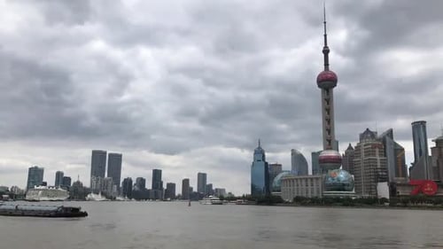 Cargo boat moves along river with modern city skyline in background