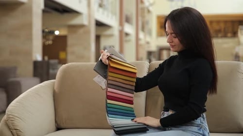 A Woman in a Store Chooses the Color of Fabric for Bed Linen