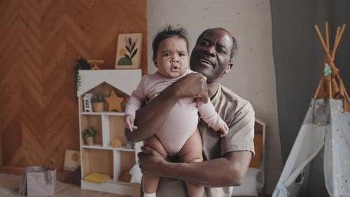 Porträt eines glücklichen afroamerikanischen Vaters mit Baby auf dem Arm