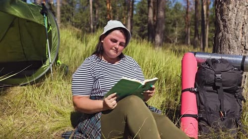 Woman Reads Book While Camping in Forest