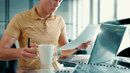 Man, laptop and document with coffee for remote work at home for information, research and typing