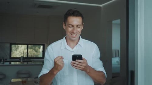 Enthusiastic Man Celebrates Success While Looking at Phone