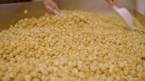 Mixing freshly cooked popcorns with salty or sweet ingredients, handheld view