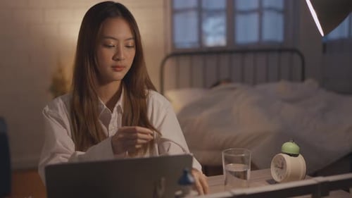 Woman Taking Pills and Drinking Water at Night