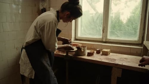 Young female artist sculpting clay pot in pottery workshop in slow motion