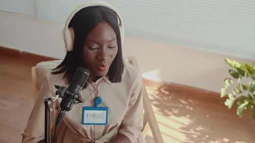Female Journalist Using Microphone during Interview in Studio
