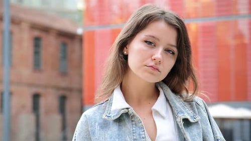 Contemplative Young Woman Gazing Thoughtfully Into the Distance While Standing in an Outdoor Area