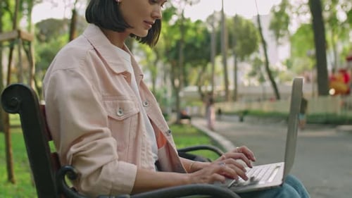 Young Woman Working Remotely on Laptop in Park