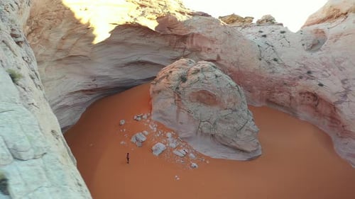 Cosmic Ashtray, Utah USA. Drone Aerial View of Lonely Person on Orange Sand Under Steep Cliffs of Un