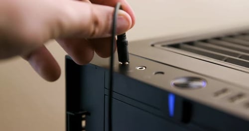 Man Plugs then Unplugs Headphone Cable into Jack on Desktop Computer