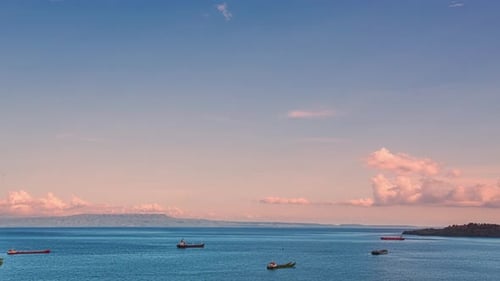 Timelapse of the ships at anchor in the ocean and large motley curly pink clouds at pink or red suns