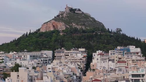 Lycabettus Hill in Athens, Greece at dusk with buildings underneath