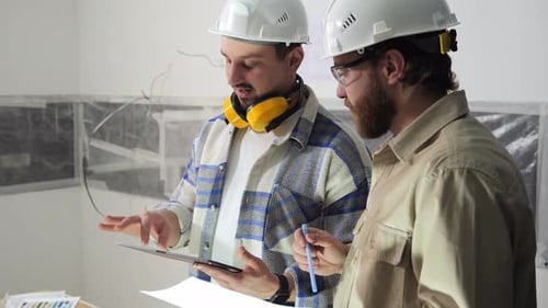 Les ingénieurs tiennent des documents et une tablette et discutent des détails de construction