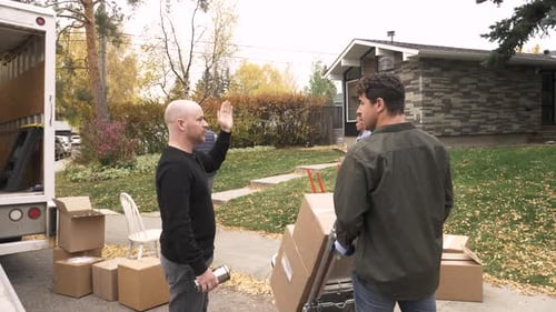 Movers unloading boxes from truck to home