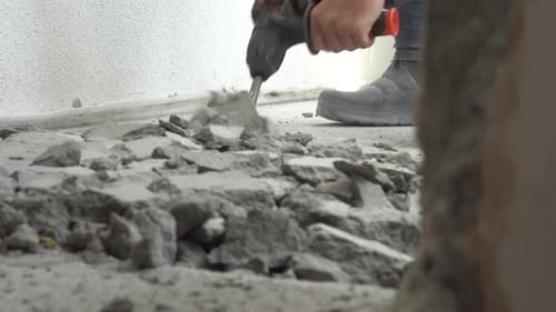 A man works with a jackhammer in an apartment. Work with a perforator
