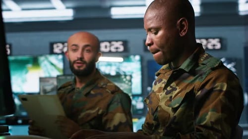 Two Military Adults Reviewing Documents in Control Room