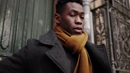 Young black man steps outside walking in city