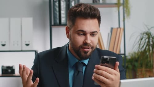 Excited Young Man Videocalling in Office Setting