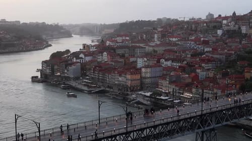 People walking across Dom Luis I Bridge between Porto and Gaia at sunset