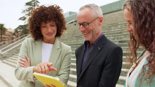 Colleagues Discussing Business on Tablet Outside