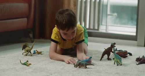 Happy Child Playing With Toy Dinosaurs on Carpet
