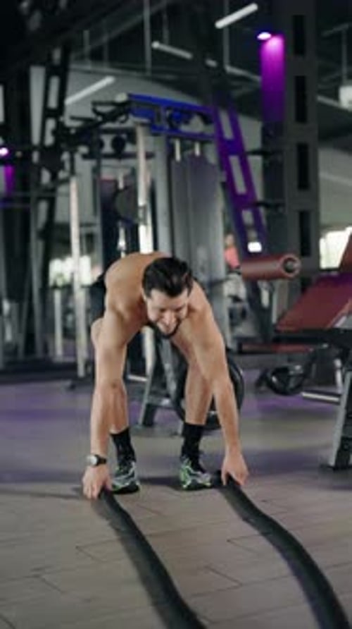 Muscular Man Performing Battle Rope Workout in a Gym