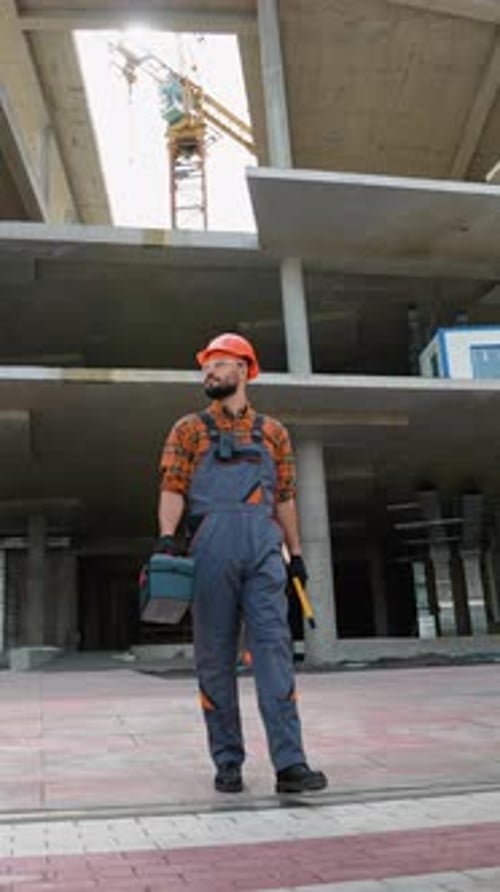 Construction Worker Walking on Building Site with Toolbox