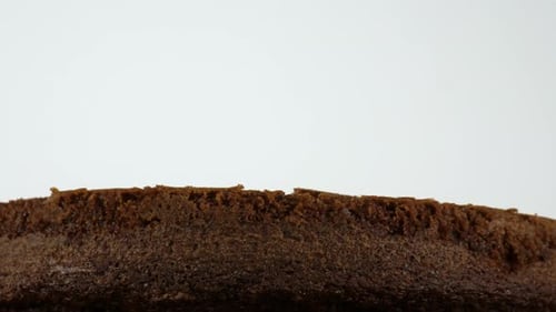 Rotating base of a chocolate cake against a white backdrop