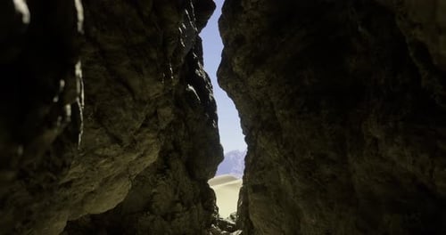 View Through Rocky Crevice Revealing Desert Landscape in Daytime
