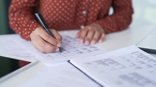 Nahaufnahme einer weiblichen Hand, die Dokumente mit einem Stift ausfüllt. Eine junge afroamerikanische Frau
