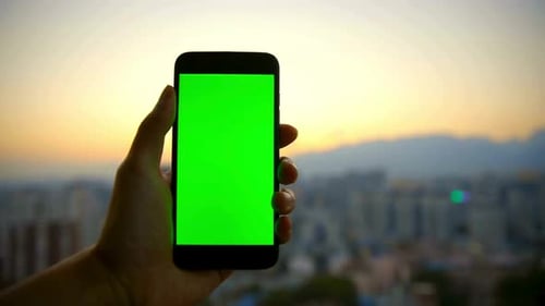 Hand Holding Phone with Green Screen City Background