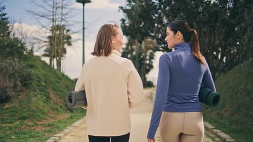 Back View Yogini Walking Alley. Active Slim Girlfriends Carrying Rubber Carpets Talking Emotional...