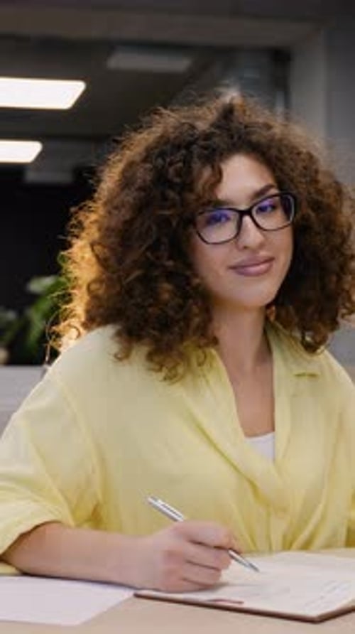 Woman with Curly Hair Writing in an Office
