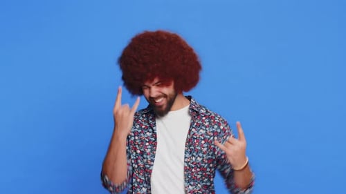 Glücklicher, fröhlicher Mann, der Rock 'n' Roll-Geste mit den Händen zeigt, cooles Schild, verrückter Ausdruck, tanzt, gewinnt den Sieg