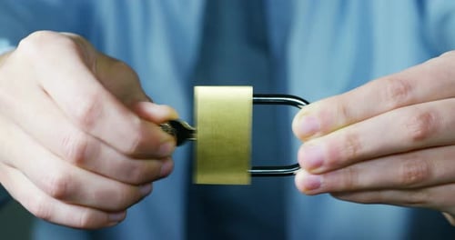 Close Up Hands Unlock Golden Padlock with Key