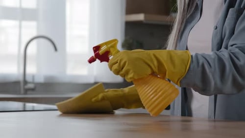 Adult Wipes Kitchen Counter With Yellow Gloves