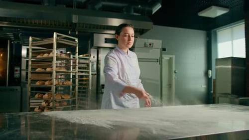 professional chef throws flour on table making flour clouds before preparing bread pastry in bakery