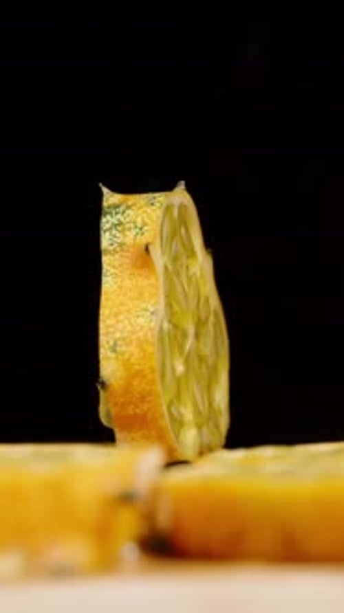 Vidéo verticale. Une tranche de concombre Kiwano tourne sur un fond noir
au milieu des morceaux